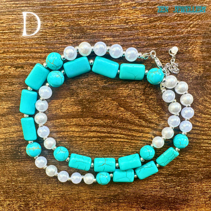 An elegant close-up of the handcrafted turquoise jewellery centrepiece featuring large turquoise stones with natural veining surrounded by pearl beads and silver decorative rings. The rustic wooden surface adds warmth and contrast to the bright gemstone colours. The necklace has a timeless bohemian charm suitable as an anniversary gift, birthday present, or statement accessory for turquoise lovers.