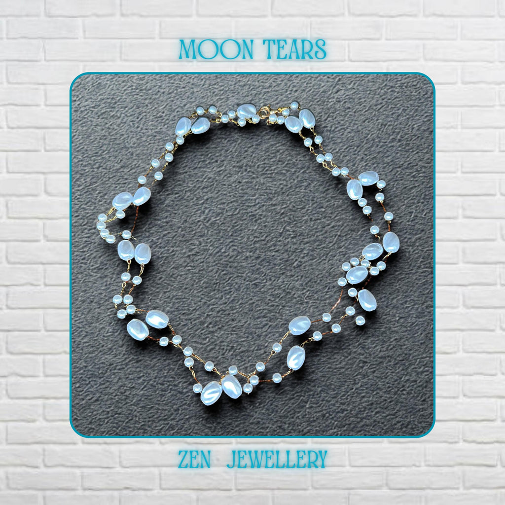 The elegant white bead necklace is displayed flat to show the flowing arrangement of oval beads, small pearl-style beads, and fine gold chain connections. The glossy white beads reflect light softly and create a feminine and romantic appearance. The lightweight handmade design feels delicate yet eye-catching with a timeless pearl-inspired aesthetic.