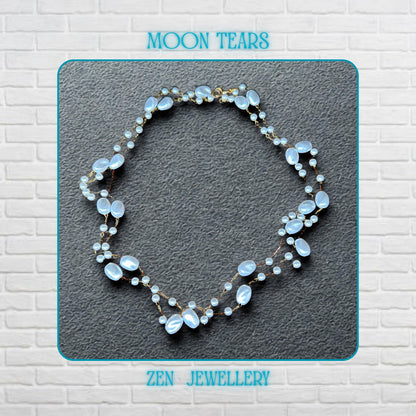 The elegant white bead necklace is displayed flat to show the flowing arrangement of oval beads, small pearl-style beads, and fine gold chain connections. The glossy white beads reflect light softly and create a feminine and romantic appearance. The lightweight handmade design feels delicate yet eye-catching with a timeless pearl-inspired aesthetic.