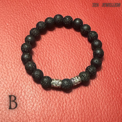 Minimalist black lava stone bracelet photographed on a textured red background to emphasise the deep black volcanic beads and polished silver spacer details. The bracelet features natural porous stones with organic matte surfaces and a handcrafted arrangement. The combination of volcanic texture and silver accents creates a stylish balance between earthy simplicity and refined elegance.