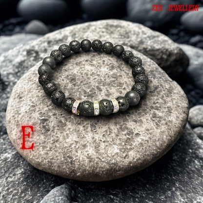 Detailed view of matte black lava beads showing natural volcanic holes and rough organic texture beside silver-tone spacer rings filled with bright white rhinestones. The bracelet creates a bold yet calming handmade look perfect for everyday jewellery styling.
