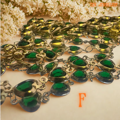 Elegant green crystal jewellery set displayed with soft blush flowers and neutral styling background. Rich emerald green faceted crystals are connected with vintage inspired gold-tone chain and sparkling rhinestone accents for added glamour and texture. The layered artistic design combines botanical elegance with romantic femininity, making this handcrafted necklace and bracelet set ideal for weddings, evening styling, festive fashion, or meaning