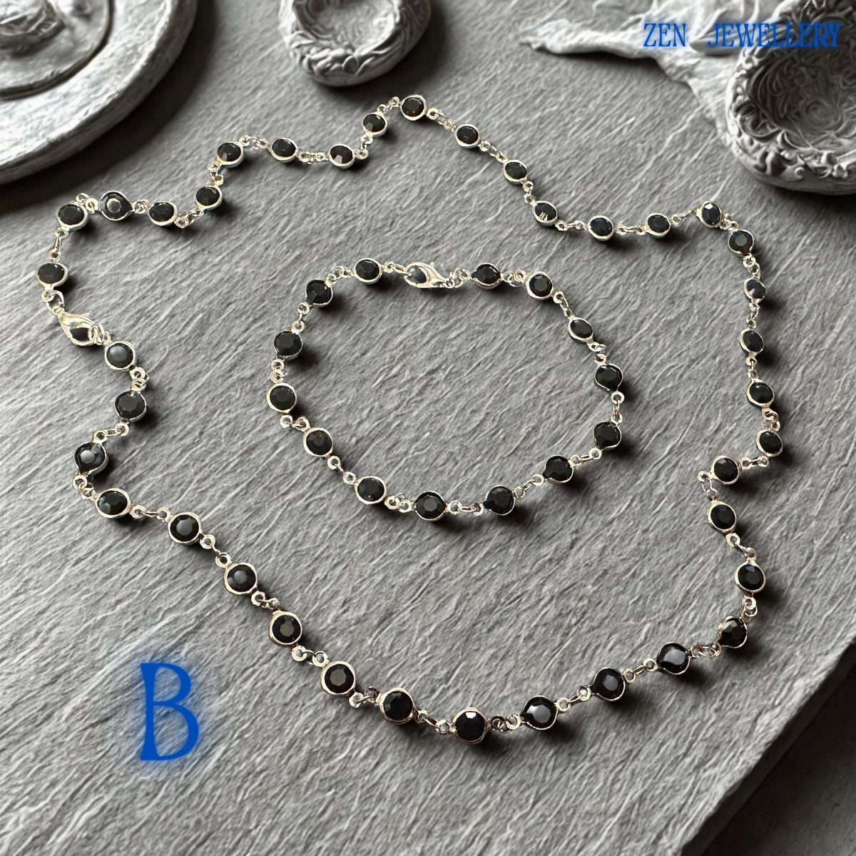 Elegant Crystal Silver necklace and bracelet set featuring faceted jet black crystals linked by a polished silver chain and matching silver clasp closure. The deep black gemstones create dramatic contrast against the bright silver metal, producing a sophisticated and contemporary appearance. The coordinated jewellery set offers gothic chic elegance, minimalist fashion appeal, and versatile styling options for evening wear, formal occasions, offic
