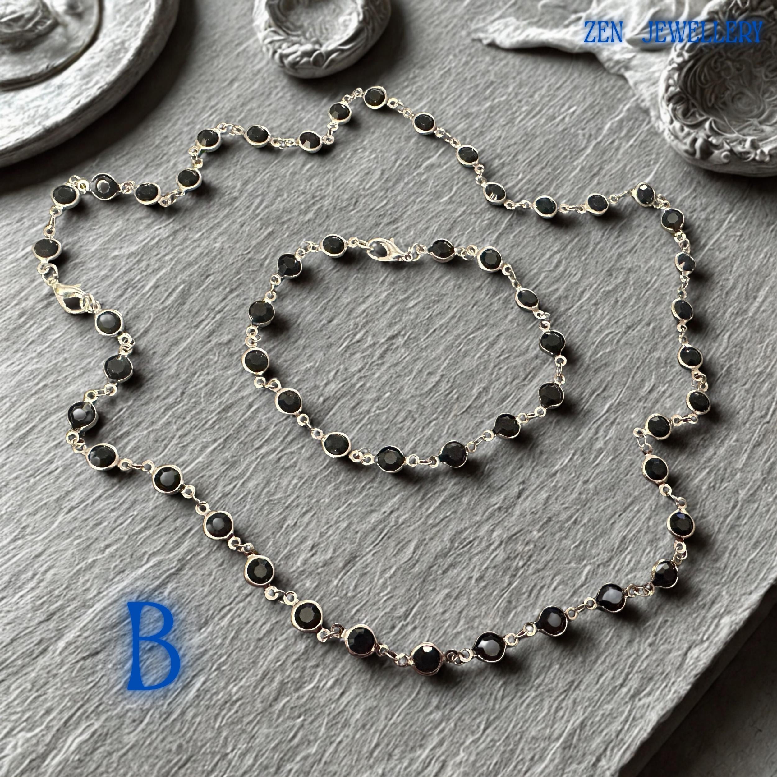 Elegant Crystal Silver necklace and bracelet set featuring faceted jet black crystals linked by a polished silver chain and matching silver clasp closure. The deep black gemstones create dramatic contrast against the bright silver metal, producing a sophisticated and contemporary appearance. The coordinated jewellery set offers gothic chic elegance, minimalist fashion appeal, and versatile styling options for evening wear, formal occasions, offic