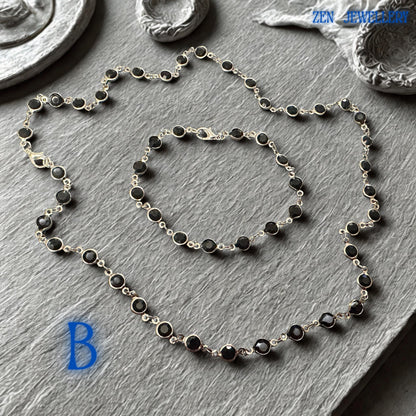 Elegant Crystal Silver necklace and bracelet set featuring faceted jet black crystals linked by a polished silver chain and matching silver clasp closure. The deep black gemstones create dramatic contrast against the bright silver metal, producing a sophisticated and contemporary appearance. The coordinated jewellery set offers gothic chic elegance, minimalist fashion appeal, and versatile styling options for evening wear, formal occasions, offic