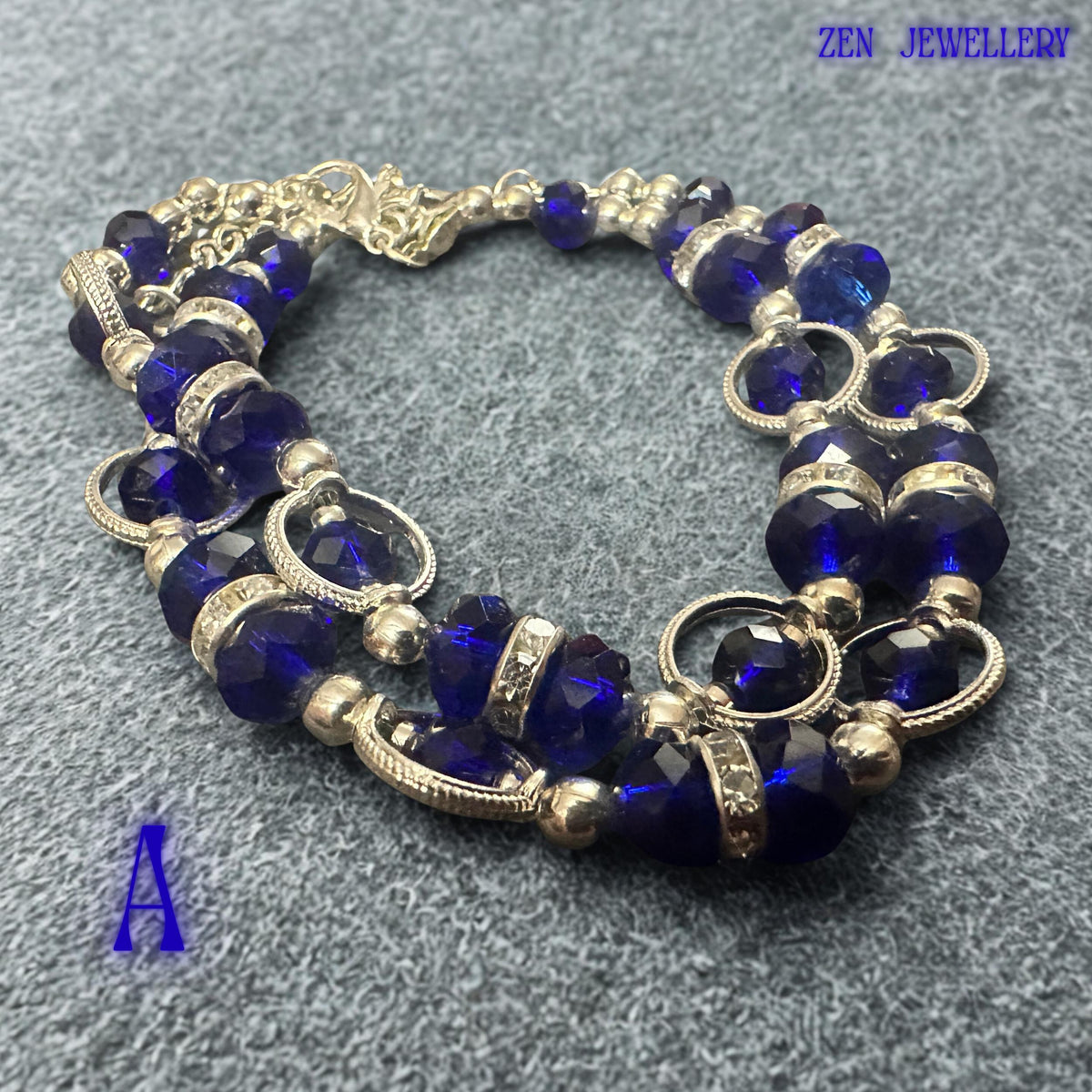 Front-facing bracelet photograph focusing on the central section where royal blue crystals and sparkling rhinestone spacers create a striking focal point. Silver-tone beads add brightness and sophistication to the overall composition. The contrast between the deep blue faceted crystals and polished metallic details creates an elegant statement accessory suitable for evening wear, celebrations, formal occasions, and stylish everyday fashion looks.