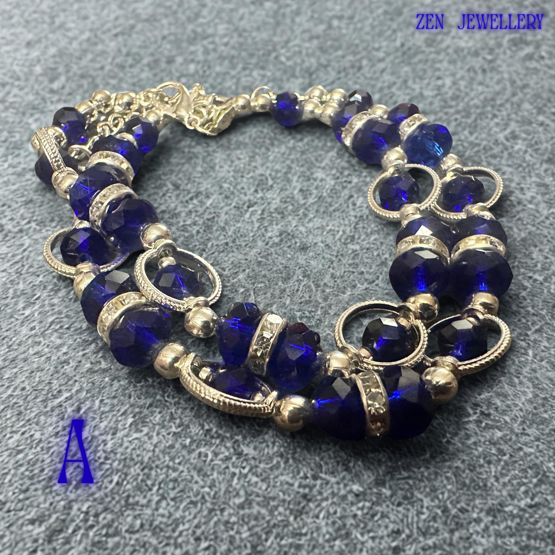 Front-facing bracelet photograph focusing on the central section where royal blue crystals and sparkling rhinestone spacers create a striking focal point. Silver-tone beads add brightness and sophistication to the overall composition. The contrast between the deep blue faceted crystals and polished metallic details creates an elegant statement accessory suitable for evening wear, celebrations, formal occasions, and stylish everyday fashion looks.