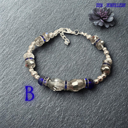 High-resolution photograph capturing the vivid sapphire and royal blue crystal tones against a softly textured fabric backdrop. Faceted crystal surfaces reflect surrounding light, producing brilliant sparkle and colour variation throughout the bracelet. Silver-tone accents and rhinestone rondelles provide luxurious contrast. The balanced symmetrical layout highlights the artisan craftsmanship and thoughtful design that make this bracelet suitable