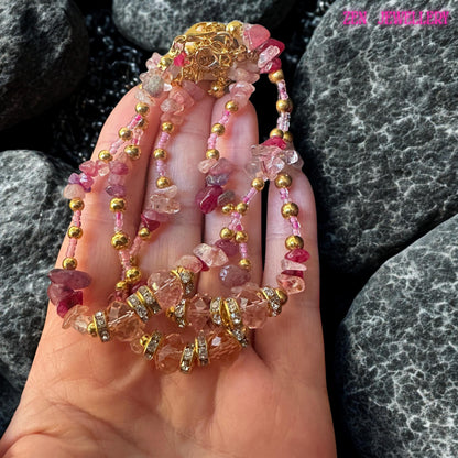 Elegant wrap bracelet made with natural pink gemstone chips in varying shades of blush, dusty rose, and deep raspberry, combined with sparkling crystal beads and gold-tone metal accents. The multi-layer design creates a rich, textured, bohemian luxury appearance. This handcrafted bracelet is designed to wrap gracefully around the wrist, offering a feminine and romantic aesthetic perfect for both everyday fashion and special event styling.