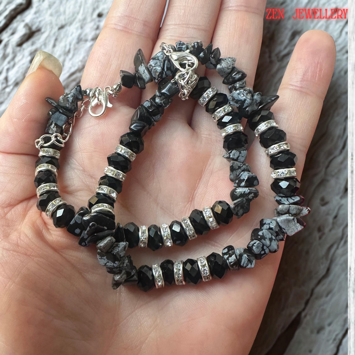 Full bracelet composition displayed on the wrist, emphasising the bold contrast between glossy black crystal beads, textured grey gemstone chips, and sparkling rhinestone spacers. The layered arrangement creates a contemporary statement jewellery piece with timeless elegance and versatility.