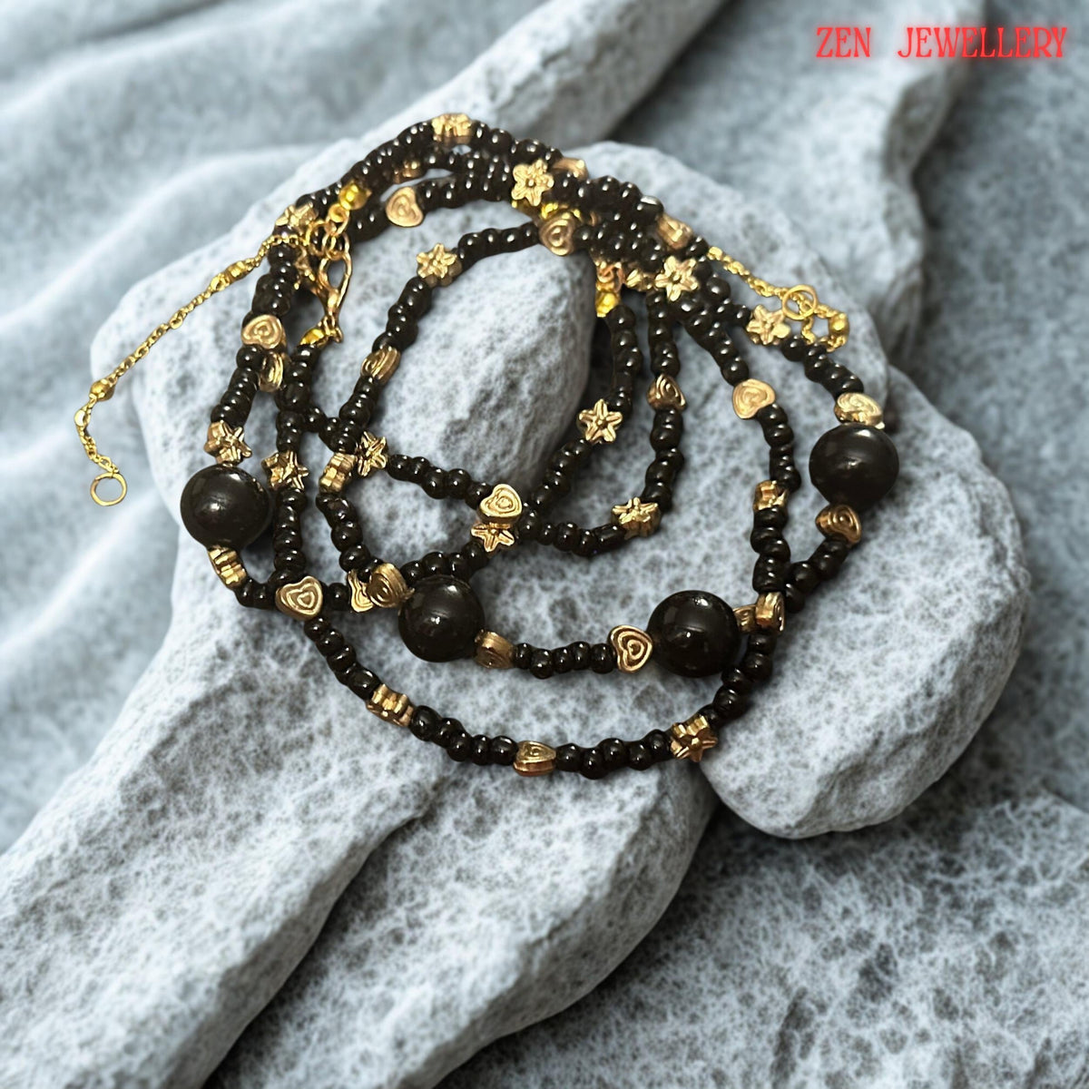 Decorative gold-tone heart accents are evenly distributed throughout the necklace and bracelet, introducing a subtle romantic touch to the overall design. The heart details are carefully integrated between the black agate beads to create visual balance and sophistication. This image helps buyers appreciate the thoughtful design elements that make the jewellery unique while maintaining a refined and versatile appearance.