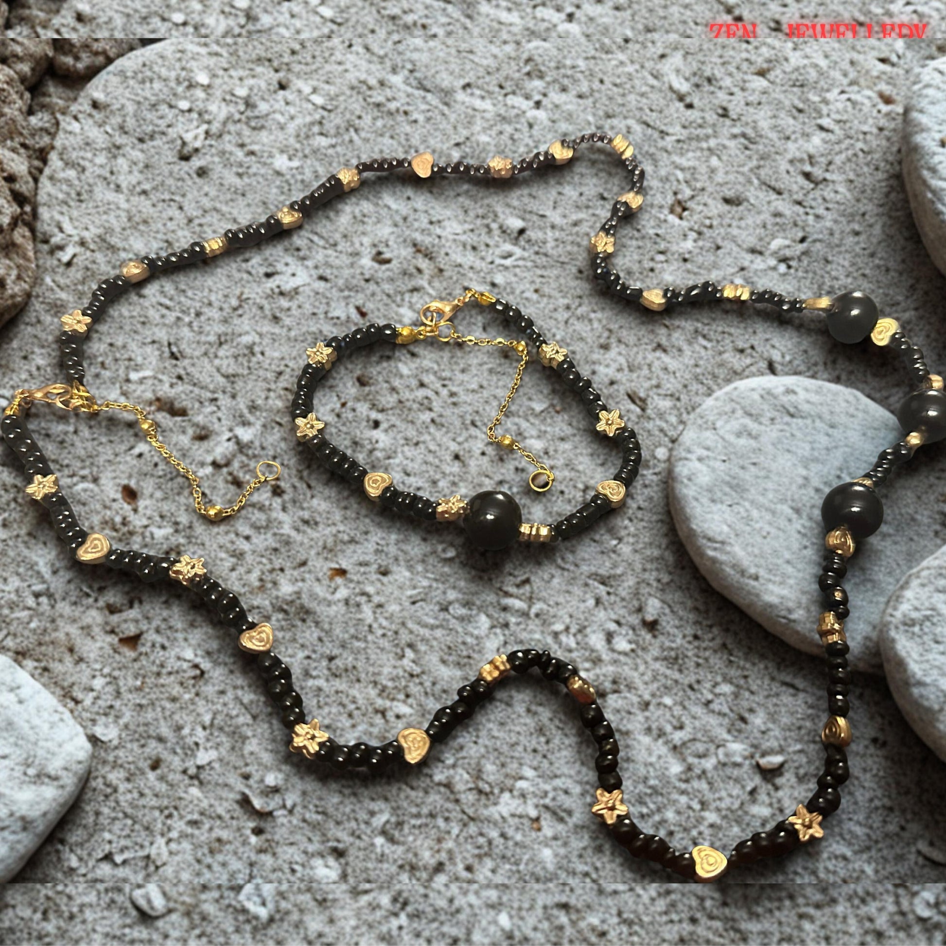 The smooth polished surface of each black agate bead reflects light gently, revealing the gemstone's elegant dark appearance and premium finish. Gold-tone floral spacer beads are carefully placed throughout the design to create visual rhythm and decorative detail. The image allows shoppers to appreciate the contrast between the glossy gemstones and textured metal accents, highlighting the sophisticated and timeless style of this jewellery set