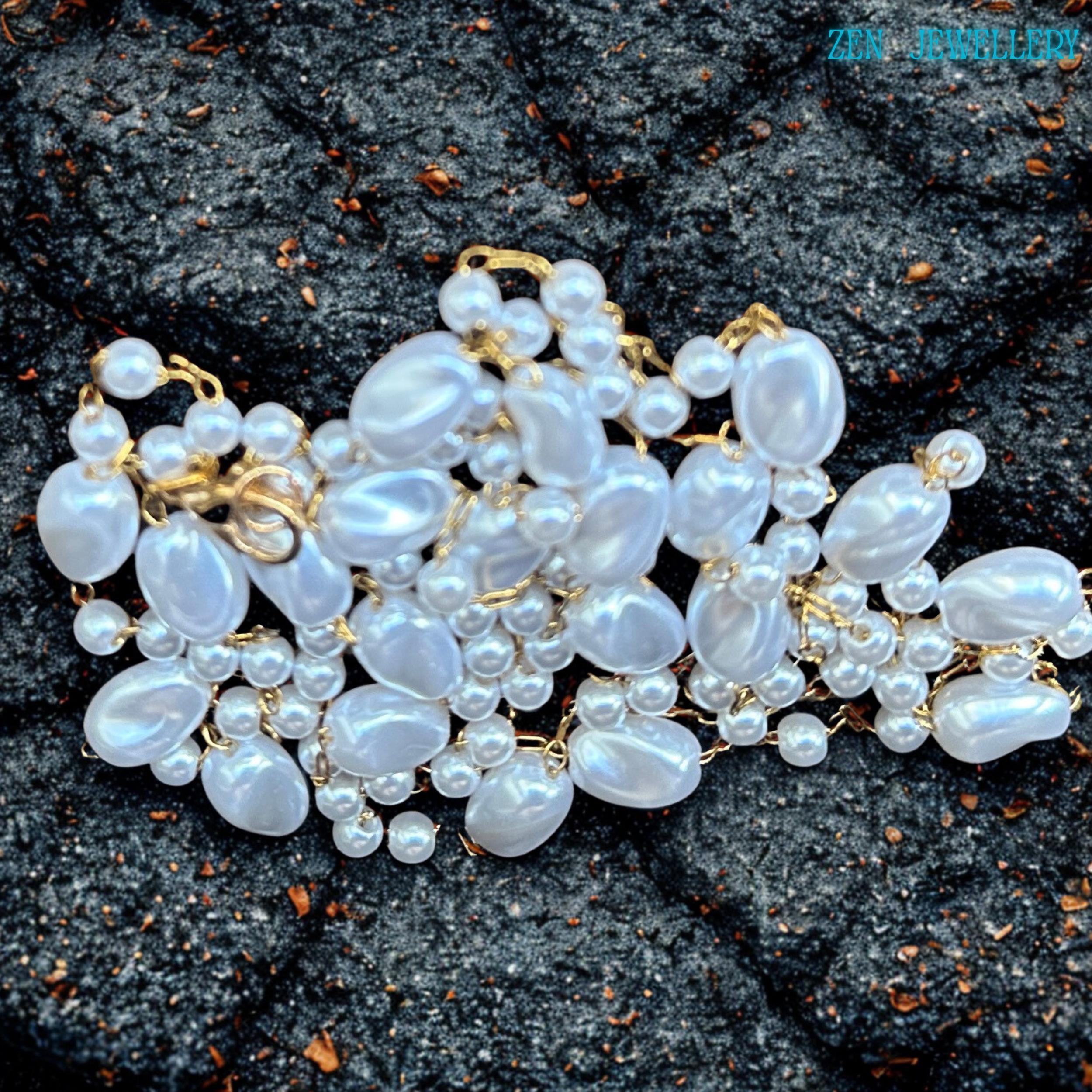 The romantic handmade necklace features flowing white pearl-style beads connected with elegant gold chain links in an airy layered design. The glossy beads create soft shine and texture while the warm gold details add refinement and elegance. The necklace works beautifully with bridal styling, summer dresses, evening outfits, or layered jewellery looks.