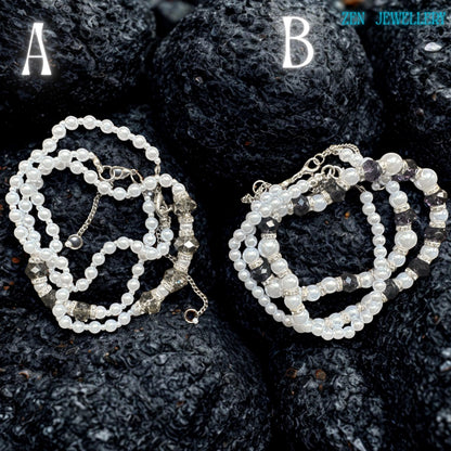 The image shows a sophisticated handmade pearl jewellery set with a matching necklace and bracelet arranged on a dark textured background. The soft white pearl beads have a glossy finish that reflects light beautifully. Smoky grey crystal accents add subtle sparkle while silver rhinestone spacers create luxurious detail and refined contrast. The lightweight layered design creates an elegant, feminine look inspired by vintage pearl jewellery and m