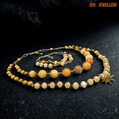 Detailed image of the layered necklace showing polished round gemstone beads and faceted champagne crystal beads alternating with gold spacers. The celestial charm detail adds a subtle statement touch to the design.