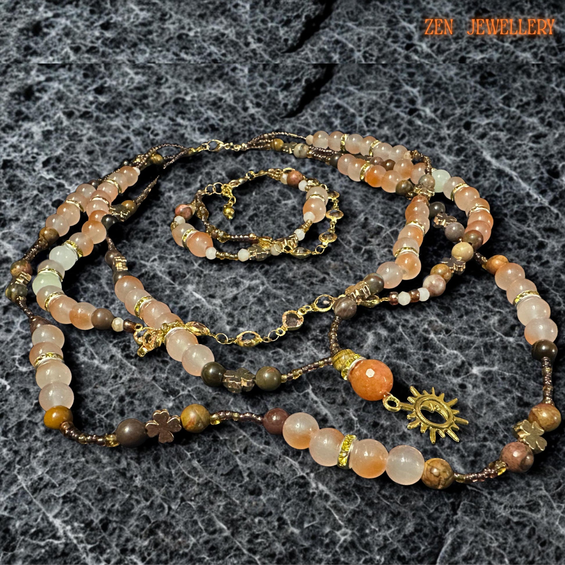 Artistic handmade gemstone jewellery set featuring aventurine beads in soft beige, peach, blush orange, caramel, and earthy brown shades arranged in a layered bohemian design. Faceted champagne crystal beads catch the light beautifully, while the gold clasp and floral charms create elegant, romantic details. The necklace lies naturally on textured dark stone surface, emphasising handcrafted quality and layered movement.