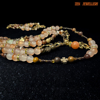 Handmade boho layered jewellery set showcasing polished aventurine gemstones combined with champagne crystal beads and delicate metallic spacer accents. Necklace features three layered strands in varying lengths with a celestial sun pendant and floral charm details. Bracelet mirrors necklace design with adjustable chain clasp and lightweight, comfortable style ideal for everyday wear or festival fashion.