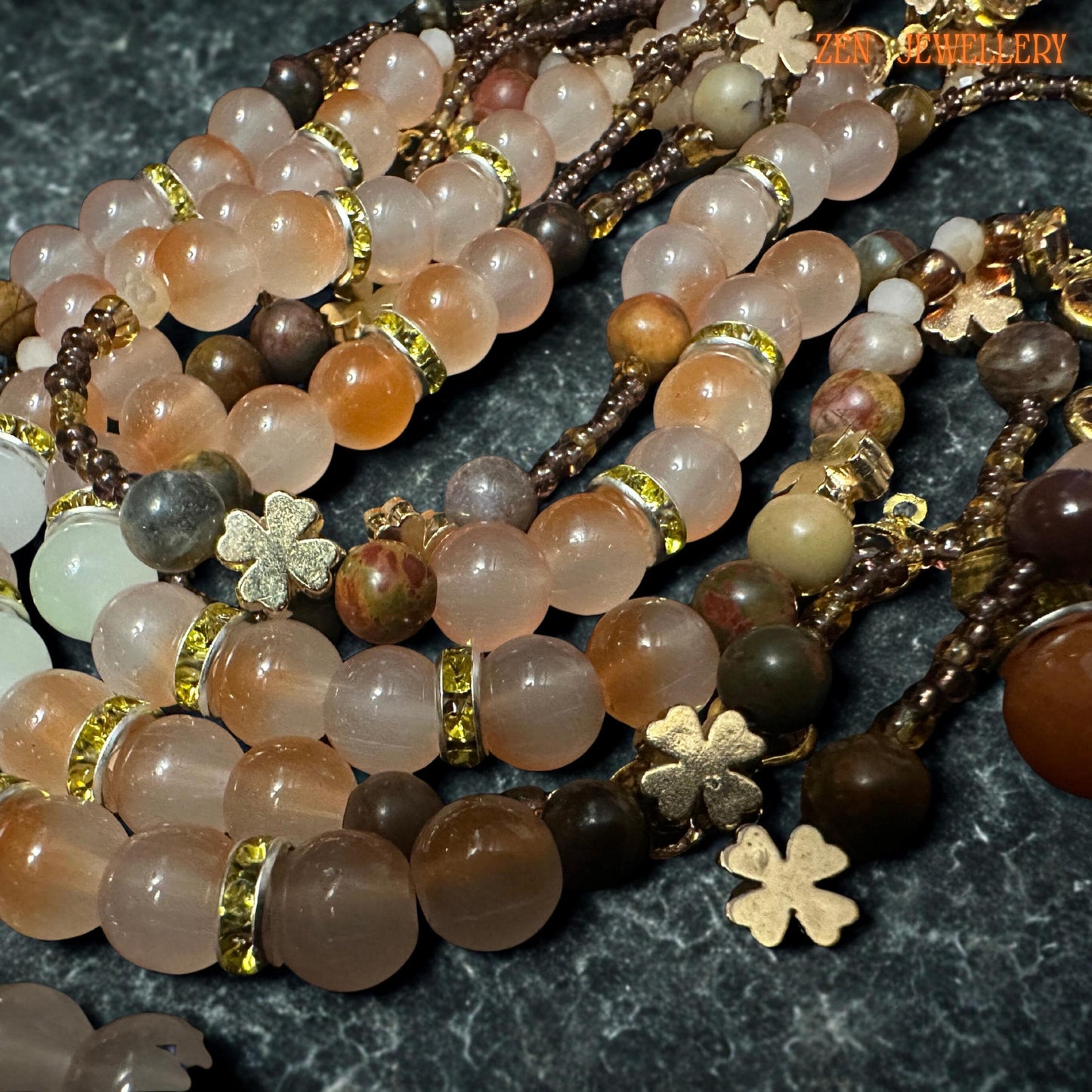 Romantic handmade gemstone necklace arranged on textured dark stone background featuring layered strands of peach, beige, caramel, and warm brown aventurine beads accented with sparkling champagne crystal beads. Gold floral charms and a celestial sun pendant add mystical artistic detail while the bracelet complements the necklace with matching colours and an adjustable clasp design.
