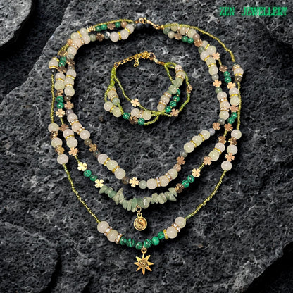 • Detailed close up of the central necklace strand featuring natural green aventurine gemstone chips arranged above a small gold yin yang charm pendant. The polished stones show soft natural texture and organic colour variation while the surrounding crystal beads and gold spacer details create luxurious layered depth and graceful handcrafted movement.