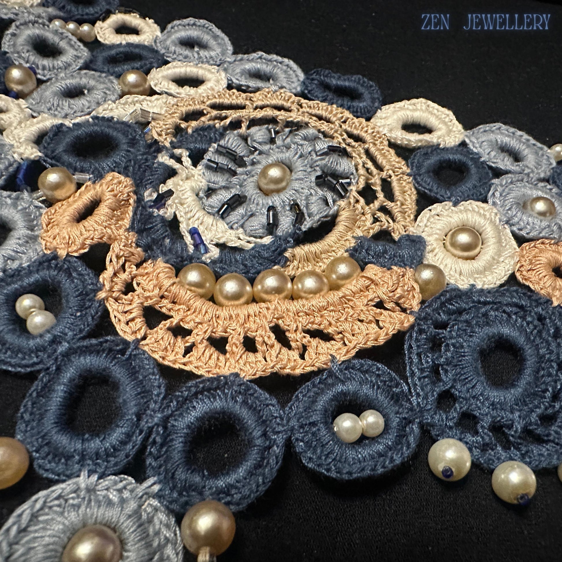 Close-up photograph of blue pearl crochet jewellery showing detailed embroidery craftsmanship, layered cotton circles, intricate lace textures and luminous pearl bead accents forming a romantic statement necklace and bracelet set with wearable art character and elegant handmade appeal.