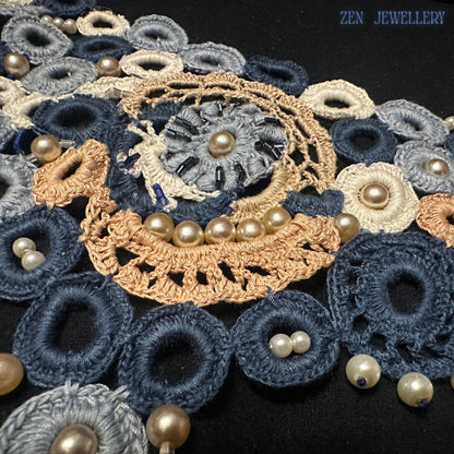 Close-up photograph of blue pearl crochet jewellery showing detailed embroidery craftsmanship, layered cotton circles, intricate lace textures and luminous pearl bead accents forming a romantic statement necklace and bracelet set with wearable art character and elegant handmade appeal.