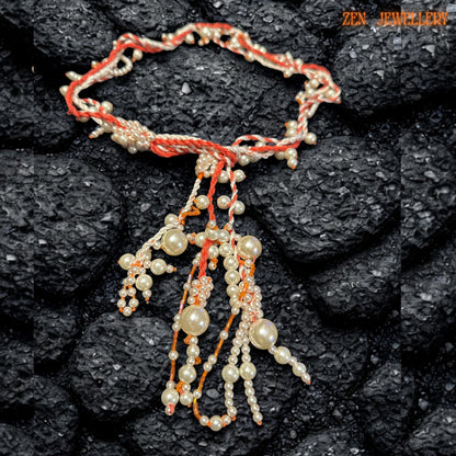 Romantic pearl tassel necklace photographed on a dark textured surface to emphasise the softness of the ivory pearl beads and warm coral crochet details. The flowing handcrafted structure combines twisted textile cords with cascading pearl strands arranged asymmetrically for a couture-inspired bohemian style. Delicate seed beads enhance the texture while the lightweight design remains comfortable to wear.