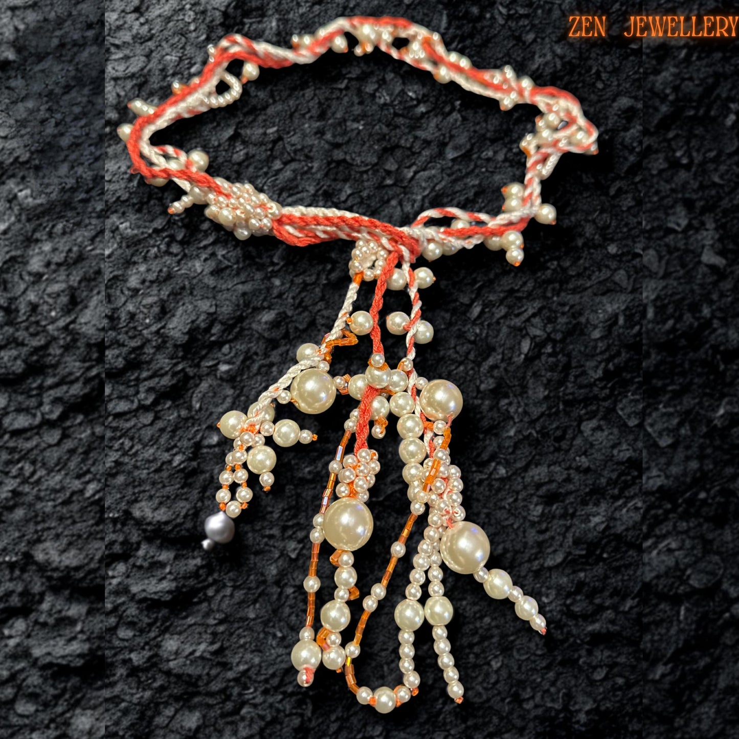 Elegant WHITE PEARL crochet necklace photographed from above to showcase the flowing arrangement of ivory pearl beads suspended from twisted coral and cream textile strands. The layered tassel design creates sculptural movement while tiny seed beads add delicate sparkle and texture throughout the necklace. The handcrafted asymmetrical structure feels artistic and organic while maintaining a luxurious, romantic appearance.