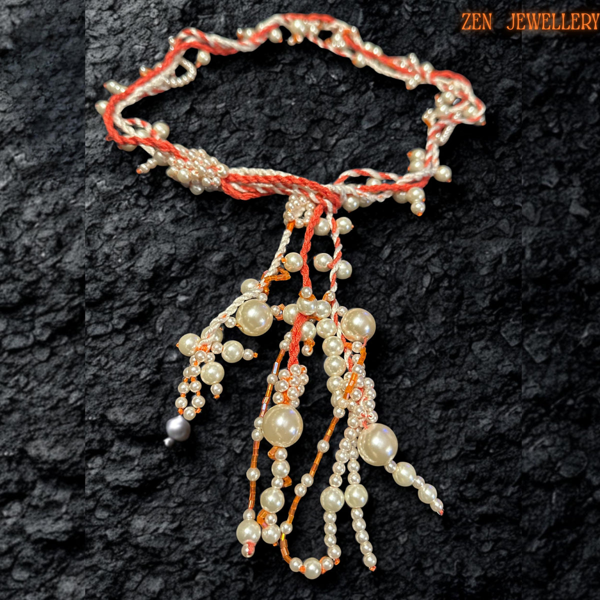 Elegant WHITE PEARL crochet necklace photographed from above to showcase the flowing arrangement of ivory pearl beads suspended from twisted coral and cream textile strands. The layered tassel design creates sculptural movement while tiny seed beads add delicate sparkle and texture throughout the necklace. The handcrafted asymmetrical structure feels artistic and organic while maintaining a luxurious, romantic appearance.