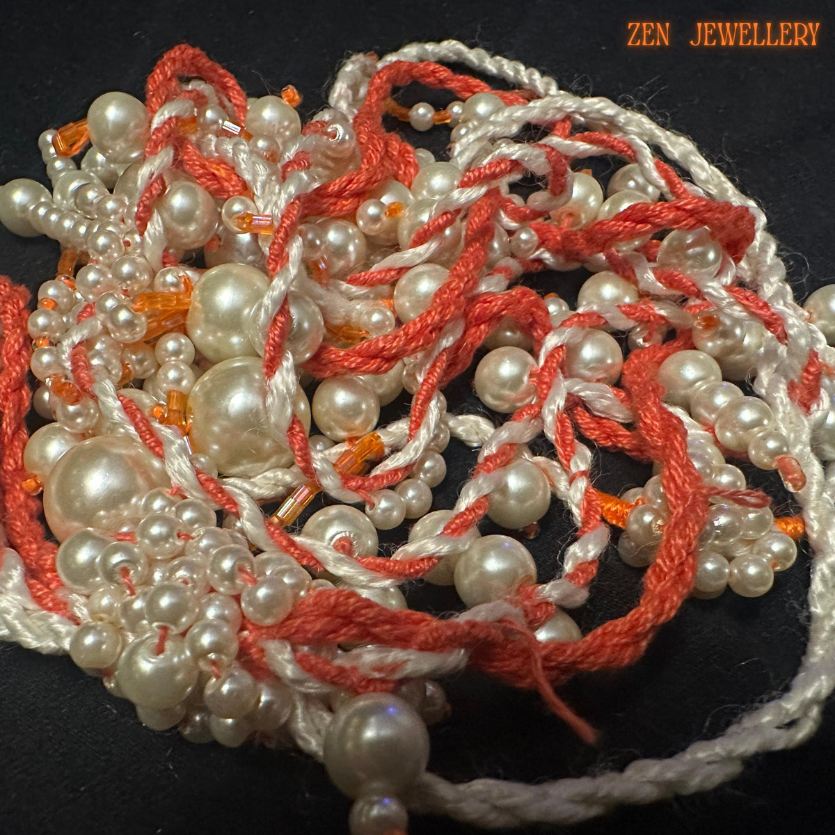 Detailed photograph of the WHITE PEARL necklace highlighting the soft shine of ivory pearl beads and flowing coral crochet structure. The necklace features dangling layered pearl tassels arranged organically to create graceful movement and luxurious asymmetrical styling. Tiny seed bead accents enhance the handcrafted detail while the twisted textile cords add warmth and artistic texture.