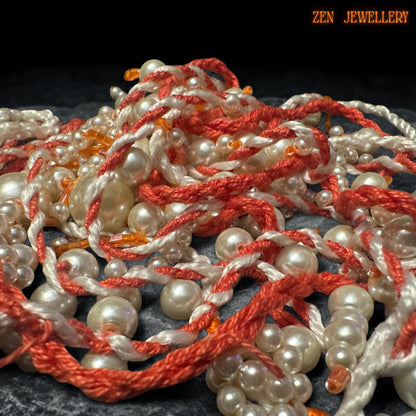 Artistic WHITE PEARL jewellery design shown from above to reveal the sculptural layered tassel arrangement and handcrafted crochet structure. The necklace features flowing ivory pearl strands attached onto twisted coral textile cords with delicate seed bead accents throughout the design. Larger pearl drops add visual depth while the asymmetrical silhouette creates graceful movement and modern bohemian elegance.