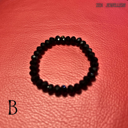 rtisan black crystal bracelet displayed in a loose, elegant curve on a textured red background. The necklace features large faceted black crystal beads paired with a bold asymmetrical black pendant framing a white iridescent shell centre. The polished surfaces and geometric pendant shape create a sophisticated statement jewellery look inspired by modern art and luxury evening accessories.