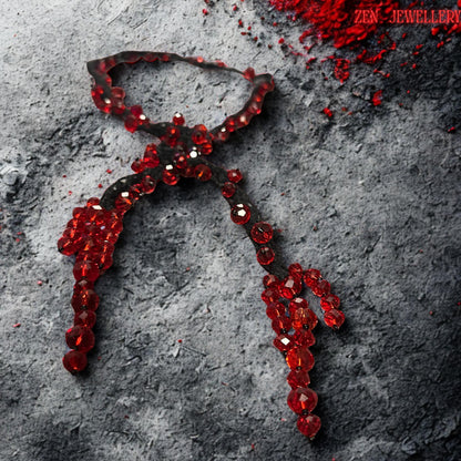 Detailed overhead photograph of the RED CRYSTAL crochet necklace highlighting the sparkling faceted bead surfaces and soft textile texture. The necklace combines sculptural braided black strands with shimmering ruby crystals that appear suspended organically along flowing lines. The asymmetrical handcrafted layout creates modern artistic movement and dramatic luxury styling. The elegant shape makes the piece ideal for gothic fashion, evening wear