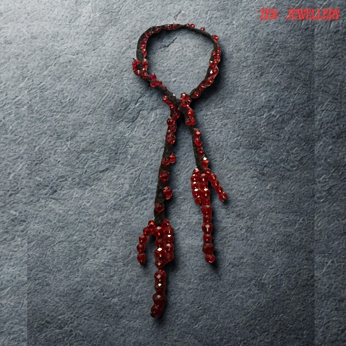 Handmade artistic necklace featuring deep ruby red crystal beads attached carefully onto black crochet cords in an asymmetrical arrangement. The sparkling faceted stones catch surrounding light and create glowing reflections while the dark textile base softens the dramatic appearance. The necklace design feels modern, expressive, and romantic with organic, flowing curves and sculptural movement. The handcrafted craftsmanship highlights individual