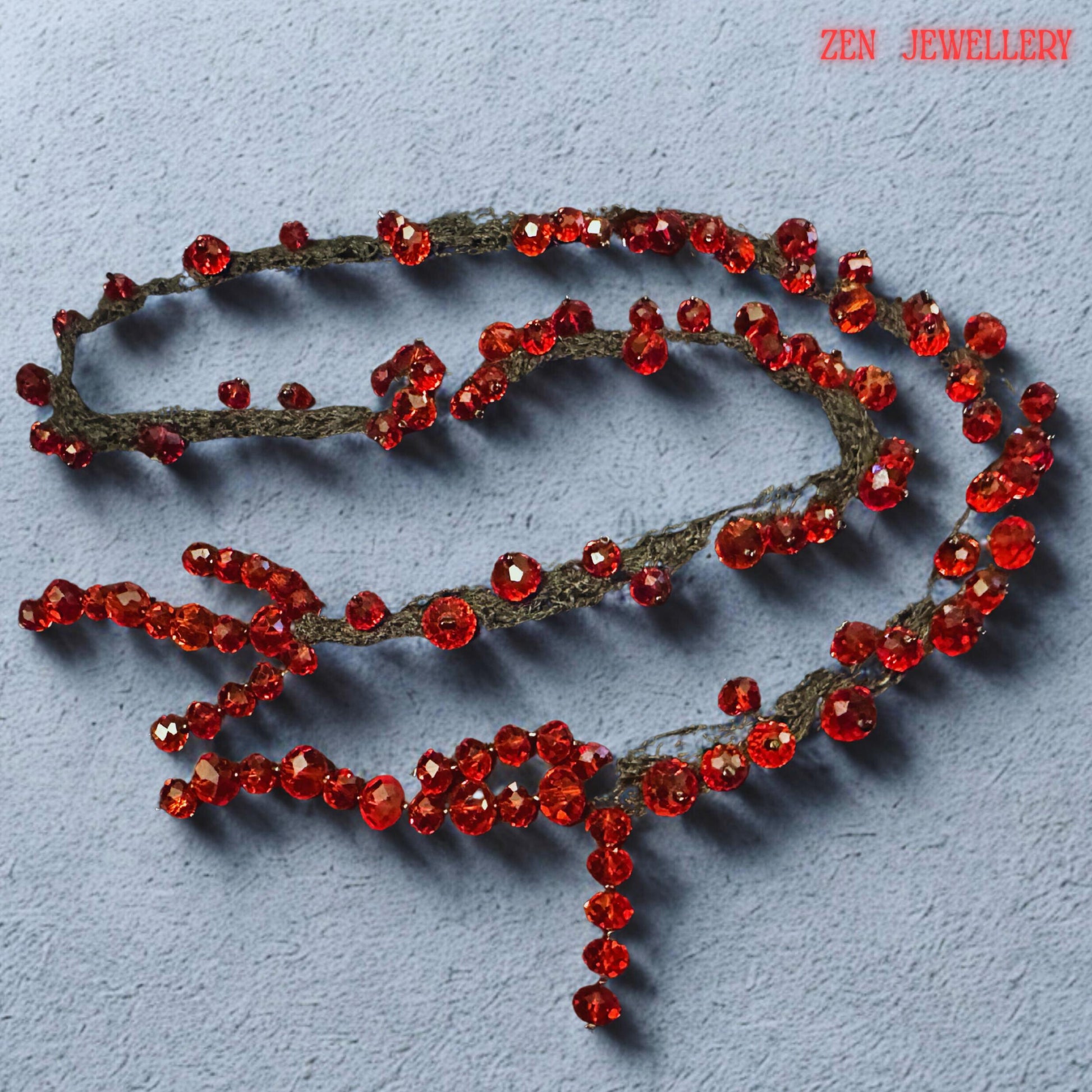 Artistic red crystal statement necklace displayed against a neutral textured background to emphasise the brilliance of the scarlet faceted beads. The necklace features multiple black crochet strands decorated with sparkling ruby crystals arranged in flowing organic curves. The handcrafted asymmetrical structure creates dramatic movement and expressive texture while remaining lightweight and wearable. The bold combination of black textile and glow