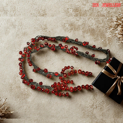 Detailed photograph of the RED CRYSTAL jewellery set highlighting the glowing ruby tones and flowing handcrafted crochet design. The faceted crystals shimmer intensely under light and create luxurious reflections across the necklace surface. The soft black crochet cords curve naturally and support the asymmetrical arrangement beautifully. The sculptural appearance combines modern bohemian style with gothic glamour, making the necklace ideal for f