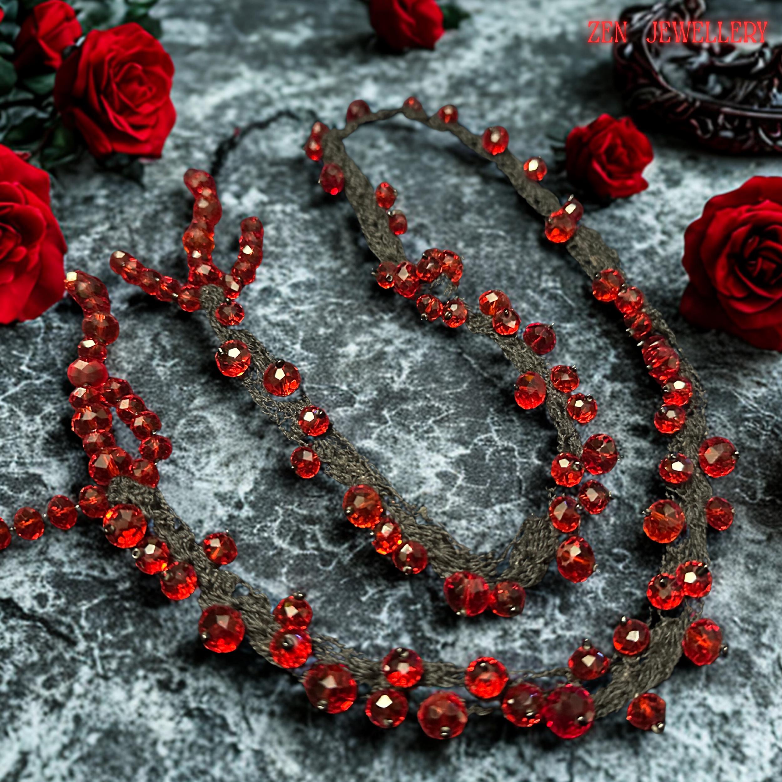 Romantic handmade RED CRYSTAL necklace featuring deep crimson faceted beads attached onto flowing black crochet cords with careful craftsmanship. The irregular crystal arrangement creates sculptural texture and natural movement while reflecting light beautifully from different angles. The soft braided strands contrast elegantly with the intense ruby sparkle and create a luxurious couture-inspired style. The necklace feels expressive, feminine, ar