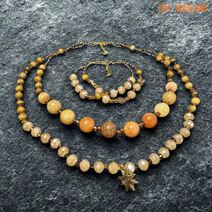 Elegant handmade jewellery piece featuring yellow jade, honey jade, and champagne crystal beads. The natural-looking gemstone tones create a calming earthy style, while the gold accents add luxury and warmth.
The necklace includes two layered strands with different bead sizes for added interest and movement. The bracelet repeats the same colour palette and handcrafted feel for a complete jewellery set.