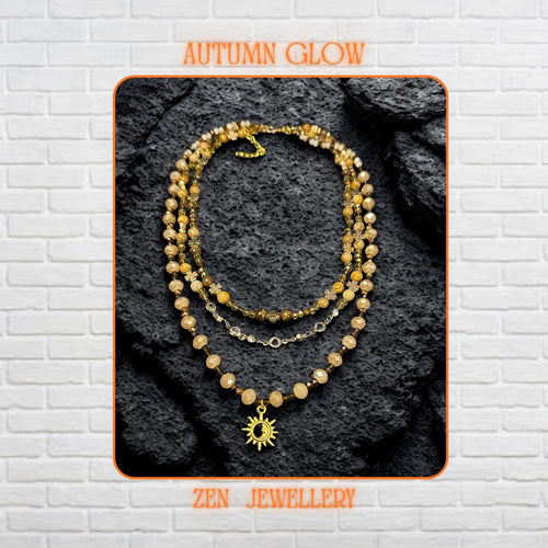 Close-up of natural gemstone beads in beige, brown, and gold shades forming a triple-strand boho necklace.