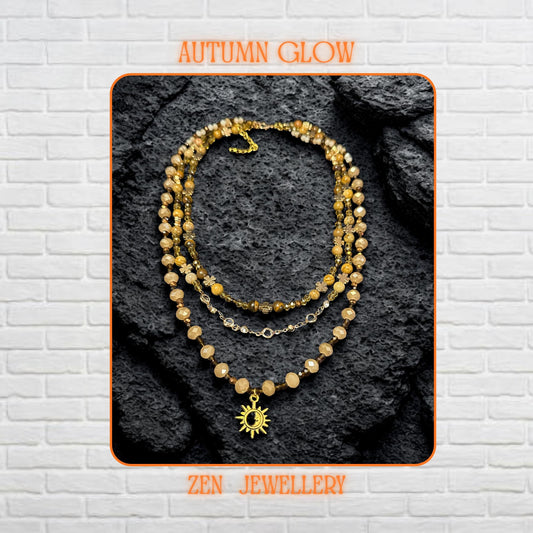 Close-up of natural gemstone beads in beige, brown, and gold shades forming a triple-strand boho necklace.