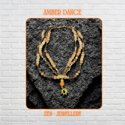 Handmade aventurine jewellery set photographed from above on black volcanic stone surface showing layered bohemian necklace with warm blush orange and champagne crystal beads. Smooth round gemstone beads reflect natural light softly while faceted crystal accents create elegant sparkle. Gold chain details, celestial charm pendant, and floral accents add feminine artistic texture. Necklace strands measure 42 cm, 44 cm, and 51 cm with adjustable bra
