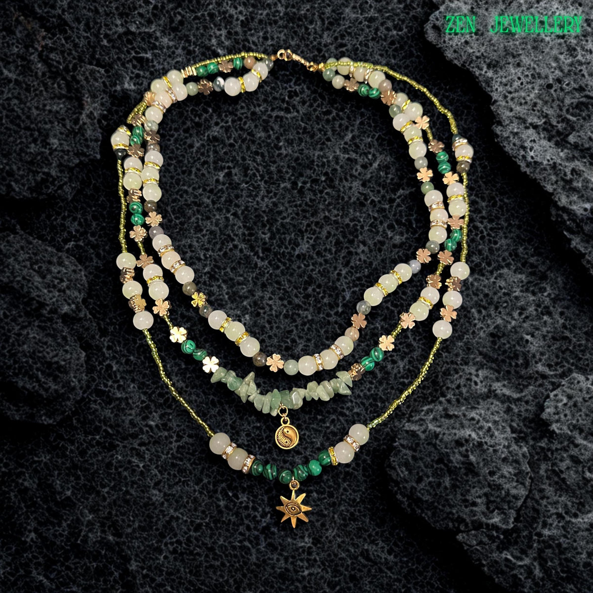 • Close up view of the layered gemstone necklace showing glossy round aventurine beads in pale green and ivory shades mixed with textured green gemstone chips and sparkling rhinestone spacers. The warm golden clasp and extension chain add elegant detail while the layered strands create graceful movement and soft earthy texture perfect for spiritual jewellery styling and feminine boho fashion collections.