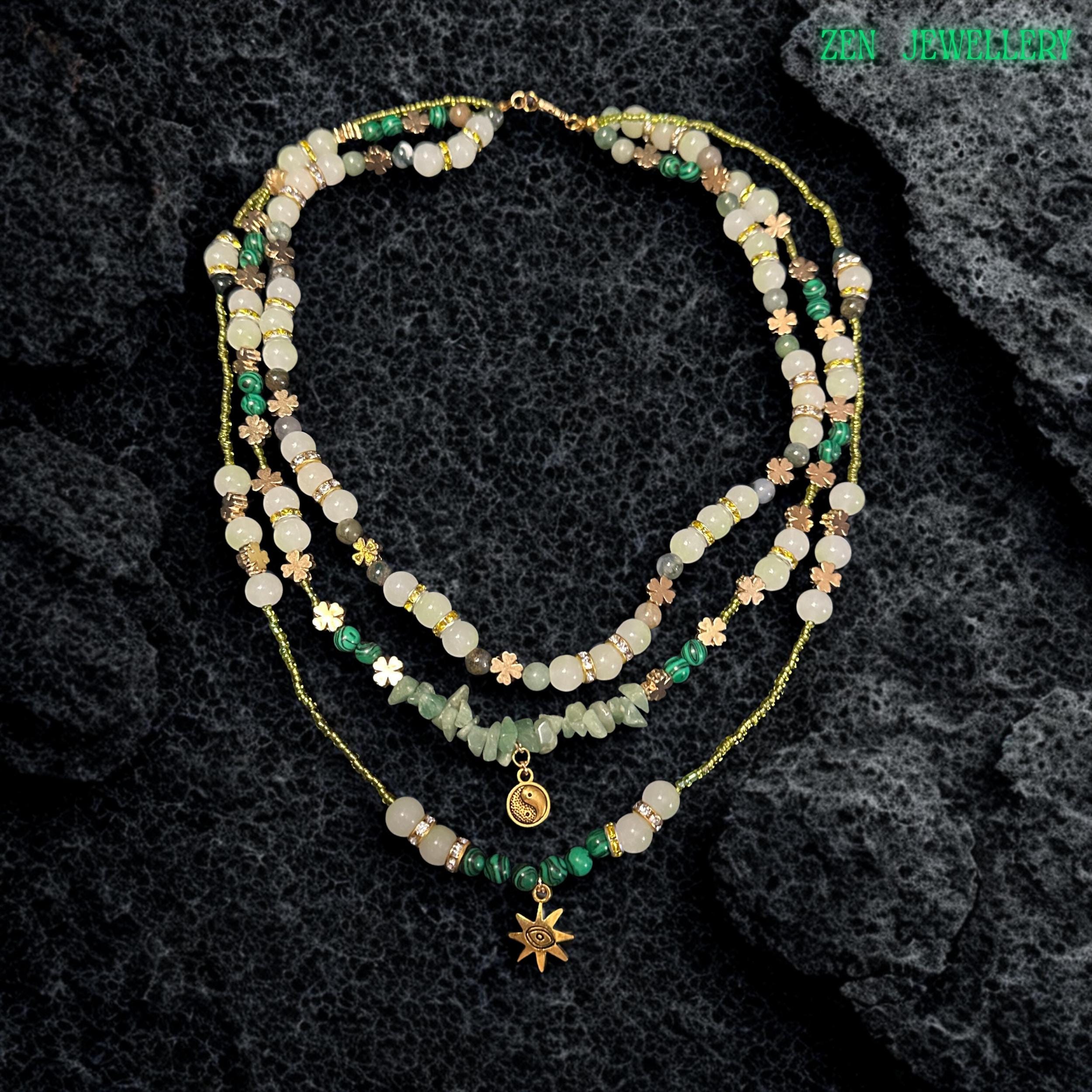 • Close up view of the layered gemstone necklace showing glossy round aventurine beads in pale green and ivory shades mixed with textured green gemstone chips and sparkling rhinestone spacers. The warm golden clasp and extension chain add elegant detail while the layered strands create graceful movement and soft earthy texture perfect for spiritual jewellery styling and feminine boho fashion collections.