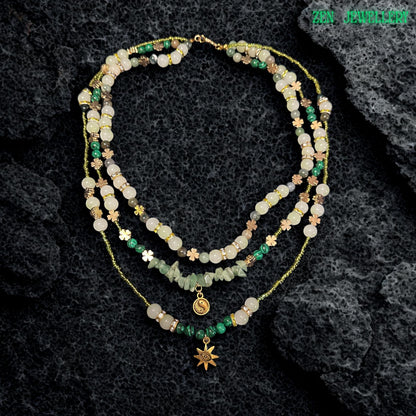 • Close up view of the layered gemstone necklace showing glossy round aventurine beads in pale green and ivory shades mixed with textured green gemstone chips and sparkling rhinestone spacers. The warm golden clasp and extension chain add elegant detail while the layered strands create graceful movement and soft earthy texture perfect for spiritual jewellery styling and feminine boho fashion collections.