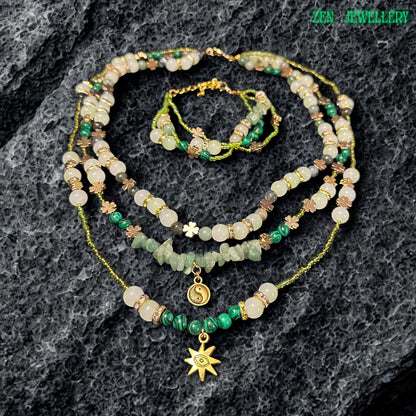 • Artistic layered crystal necklace featuring soft green aventurine beads, ivory gemstone accents, shimmering metallic seed beads, and sparkling rhinestone spacers combined with celestial jewellery charms. The elegant handcrafted design includes a gold sun pendant and yin yang charm that add mystical spiritual symbolism and romantic bohemian elegance to the overall gemstone jewellery composition.