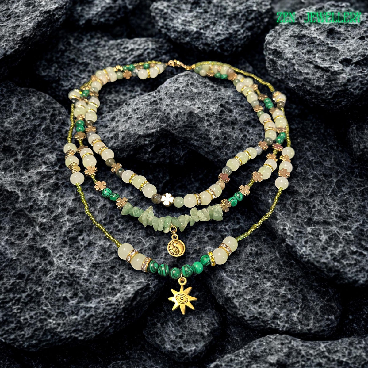 • Handmade bohemian gemstone necklace and bracelet set featuring natural aventurine stones, creamy crystal beads, floral spacer charms, and delicate gold details arranged beautifully on a textured black stone surface. The rich contrast between the dark background and soft green gemstones highlights the elegant handcrafted finish and the artistic layered structure of the jewellery set.