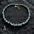 Close-up image of Blue Crackle Agate gemstone beads showing detailed crackled vein textures in deep turquoise, black, and ocean blue shades separated by polished silver spacer beads that reflect light softly against the dark background, highlighting the natural stone patterns, handcrafted jewellery construction, layered bead arrangement, and elegant celestial styling details that create a luxurious bohemian appearance.