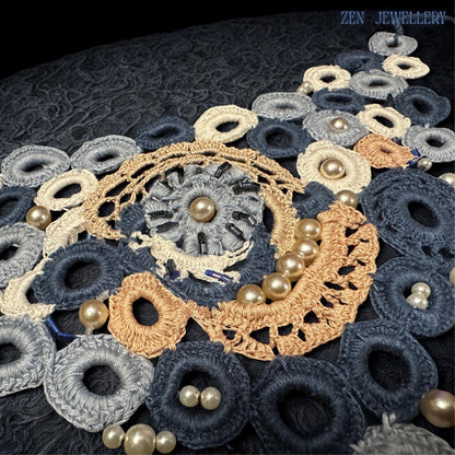 Romantic crochet necklace with pearl accents arranged in a dramatic bib silhouette featuring intricate embroidery, lace-inspired circles and layered textures in navy blue pale blue cream and ivory tones designed as a standout accessory for weddings elegant dresses and luxury bohemian outfits.