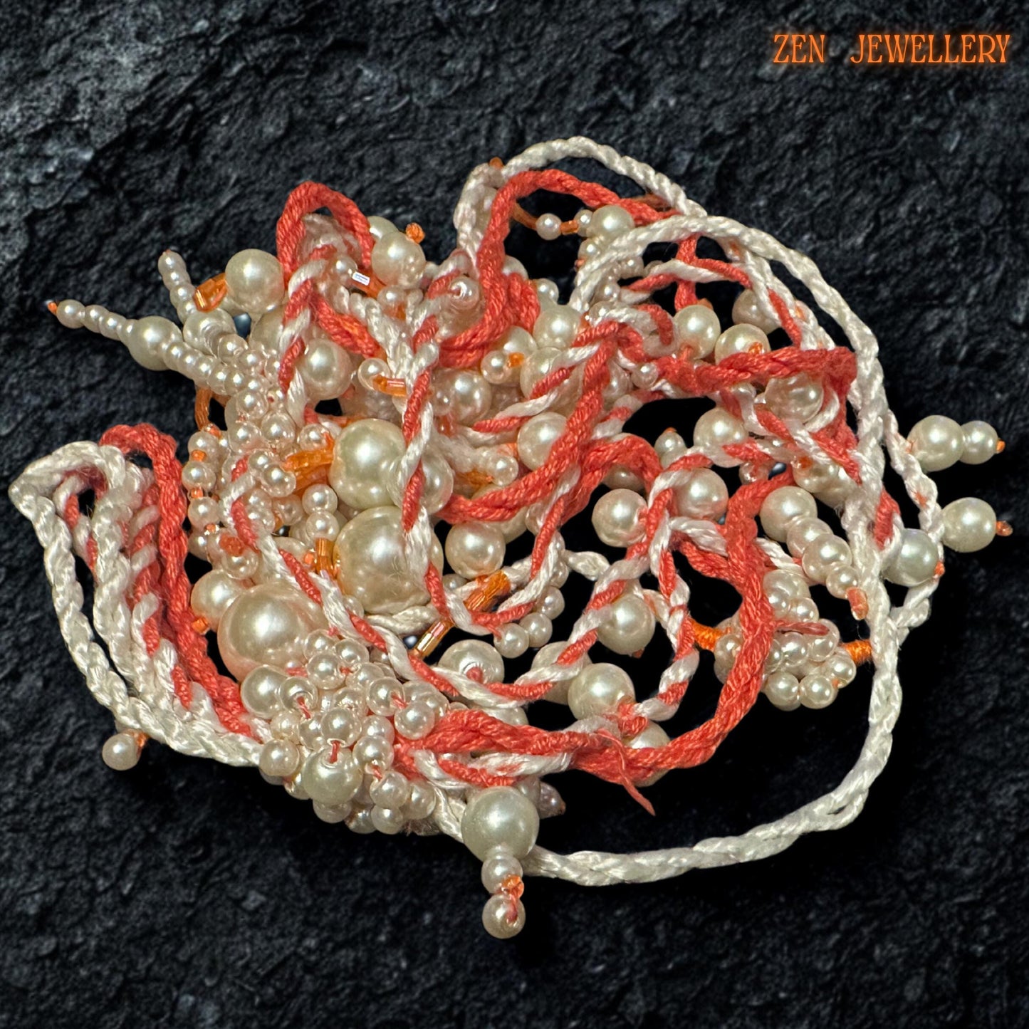 Handmade WHITE PEARL statement necklace photographed on a textured black surface to emphasise the flowing layered pearl strands and intricate crochet details. The necklace combines warm coral orange textile cords with soft ivory pearls in mixed sizes for a romantic artistic look. The dangling tassel elements create natural movement while delicate seed bead accents add depth and handcrafted texture.
