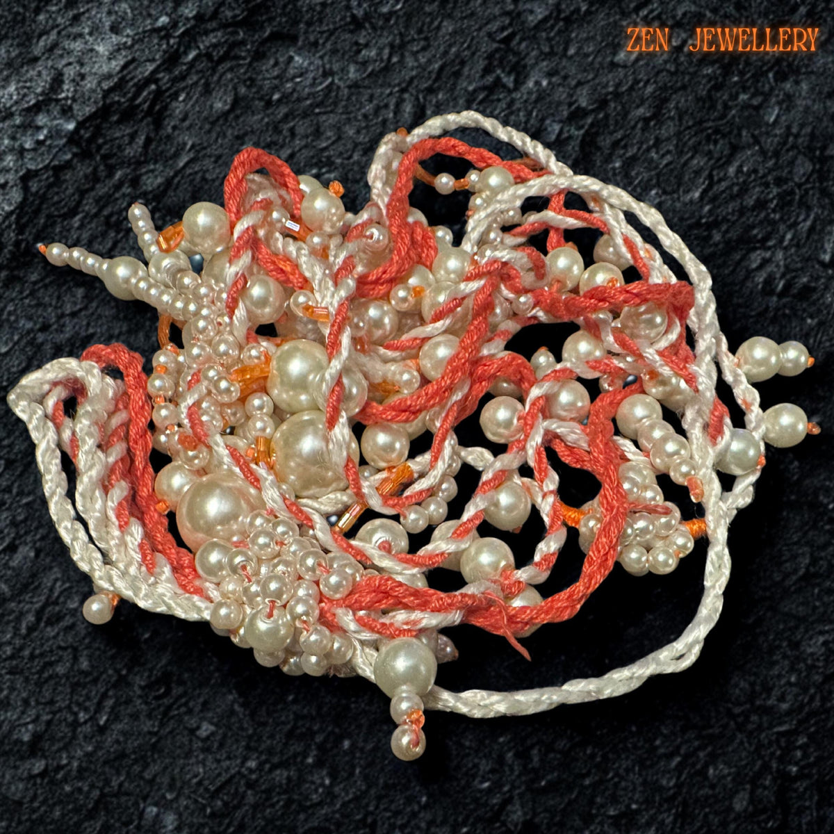 Handmade WHITE PEARL statement necklace photographed on a textured black surface to emphasise the flowing layered pearl strands and intricate crochet details. The necklace combines warm coral orange textile cords with soft ivory pearls in mixed sizes for a romantic artistic look. The dangling tassel elements create natural movement while delicate seed bead accents add depth and handcrafted texture.