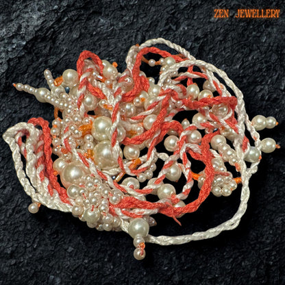 Handmade WHITE PEARL statement necklace photographed on a textured black surface to emphasise the flowing layered pearl strands and intricate crochet details. The necklace combines warm coral orange textile cords with soft ivory pearls in mixed sizes for a romantic artistic look. The dangling tassel elements create natural movement while delicate seed bead accents add depth and handcrafted texture.